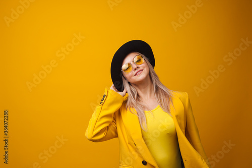 Cheerful trending young woman in bright clothes on yellow background, copy space. Cool blonde © Alexander
