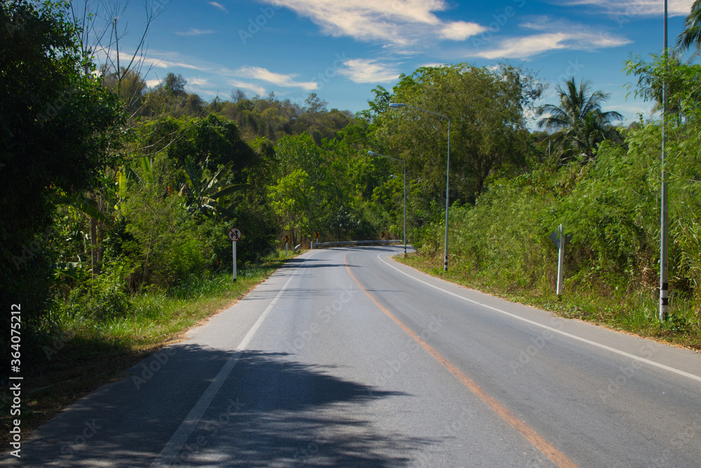 This unique photo shows a country road which runs through the wild jungle of Thailand and ends with a right turn. You can see the green nature This unique photo shows a country road which runs through the wild jungle of Thailand and ends with a right turn. You can see the green nature