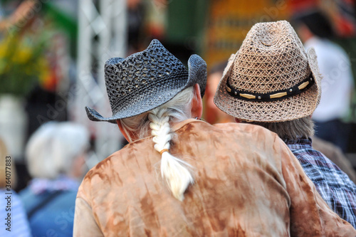 Ein Ã¤lteres Paar in Western und Country Outfit und Cowboyhüten auf einer Open-Air-Veranstaltung vor der Bühne - selektiver Fokus, viel Copy Space photo