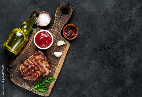 
Grilled beef steak with spices served on a cutting board on a stone background with copy space for your text