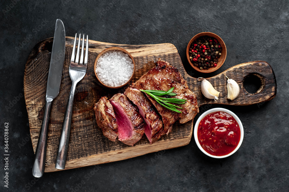 
Grilled beef steak with spices served on a cutting board on a stone background