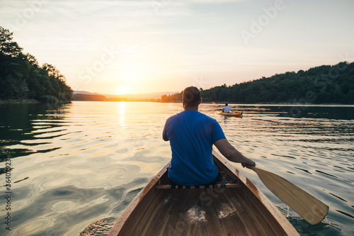 Fotografie Rear view of men paddling canoe and kayak at sunset lake