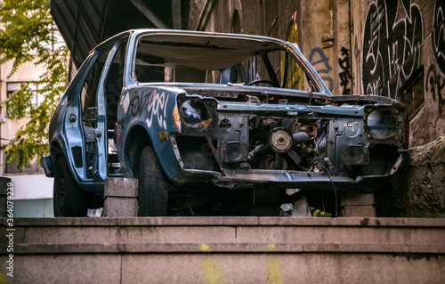 an abandoned scrap car, standing apart on the sidewalk, outdoor.