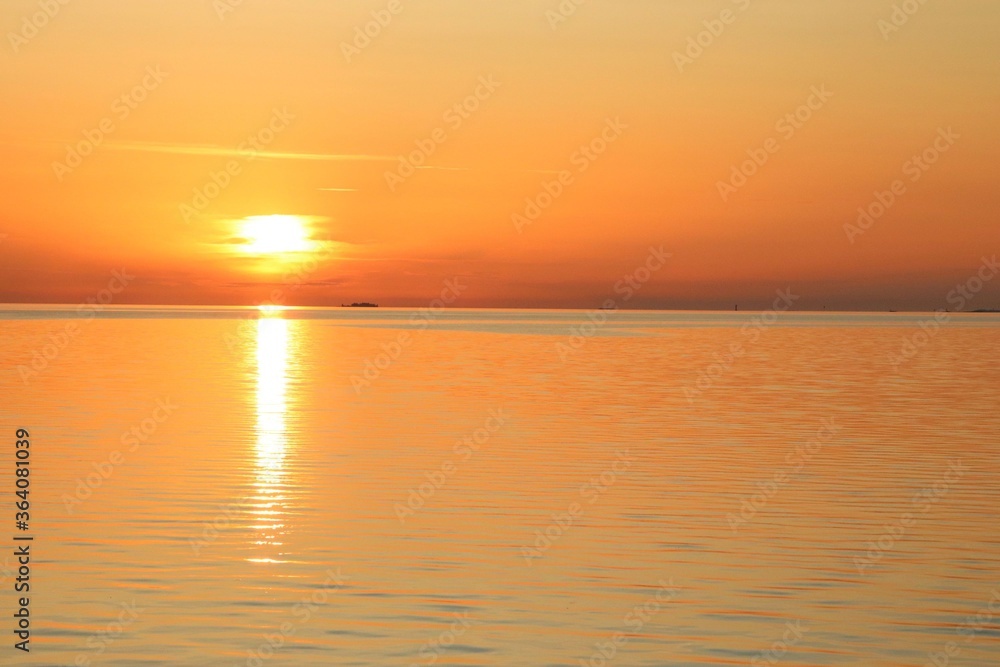 Golden sunset over the sea. Beautiful orange and yellow colors in calm water.