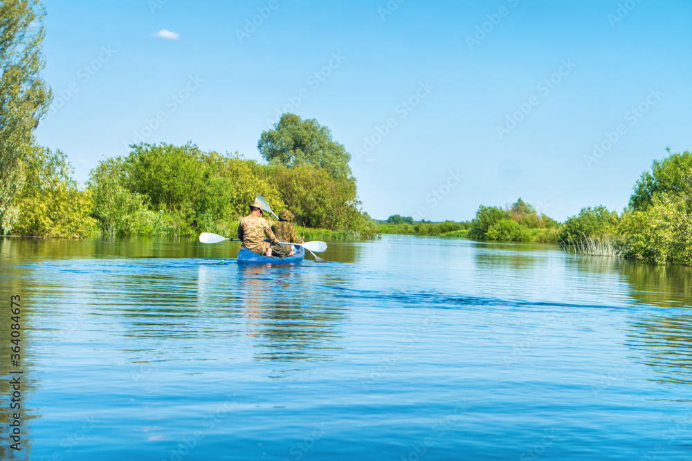 People on kayak trip on blue river landscape and green forest with trees blue water clouds sky
