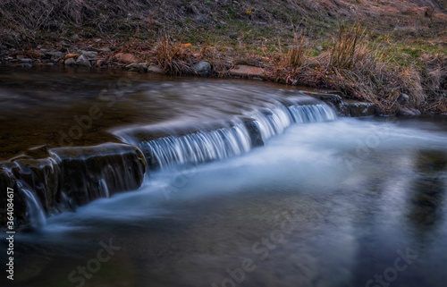 Fototapeta Naklejka Na Ścianę i Meble -  Water threshold on river Zalotomyatyi in carpatian mountains and green forest. National park Skolivski Beskidy. April 2020. Long exposure shot.