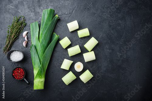 Chopped green leeks oninon uncooked with herbs ingredients , on textured black background top view with space for text.