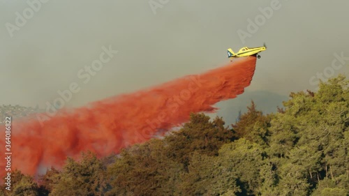 Fire fighter plane drops fire retardant on a forest fire in the hills photo