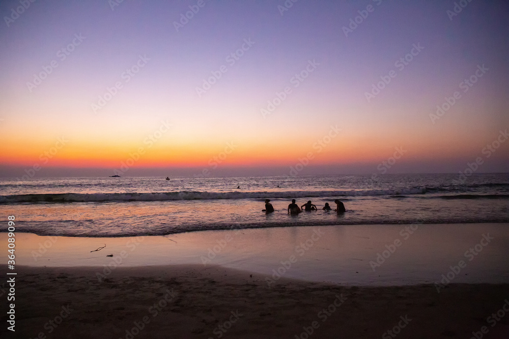Idyllic landscape with teenagers (childs of tourists from  England )  at  Wonderful sunset on the Nirvana  beach in South India in Kumta region . Unrecognizable persons . 
