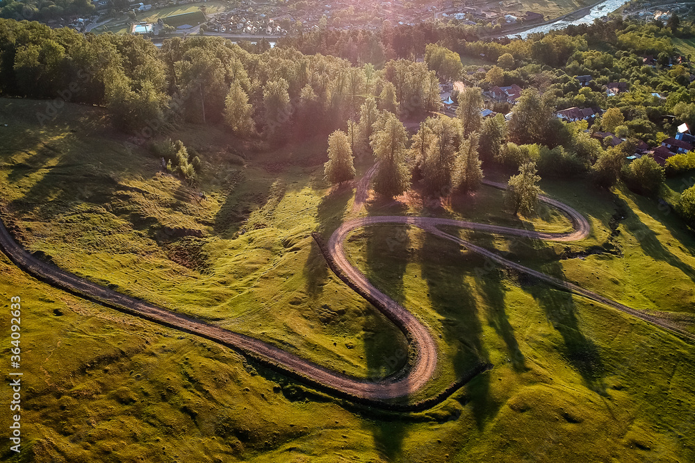 Beautiful curvy country road with fir trees in background during the sunrise with rays of light. Comanesti, Romania. Beautiful curvy country road with fir trees in background during the sunrise with rays of light. Comanesti, Romania.