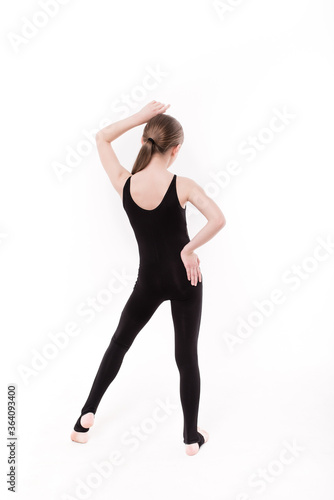 Girl gymnast in a black gymnastic leotard on a white background isolated. Young girl doing gymnastic exercise in black leotard