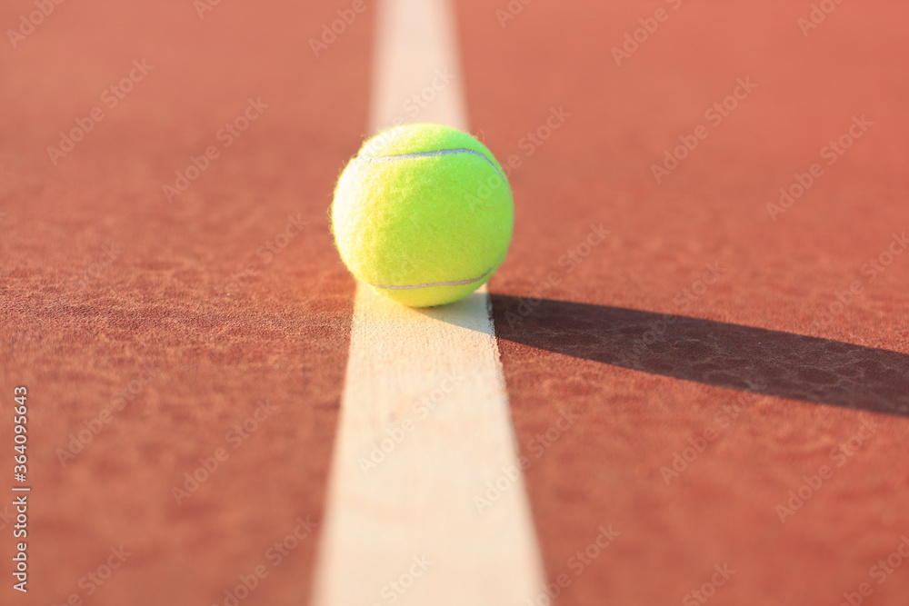 Bright greenish yellow tennis ball on the line.