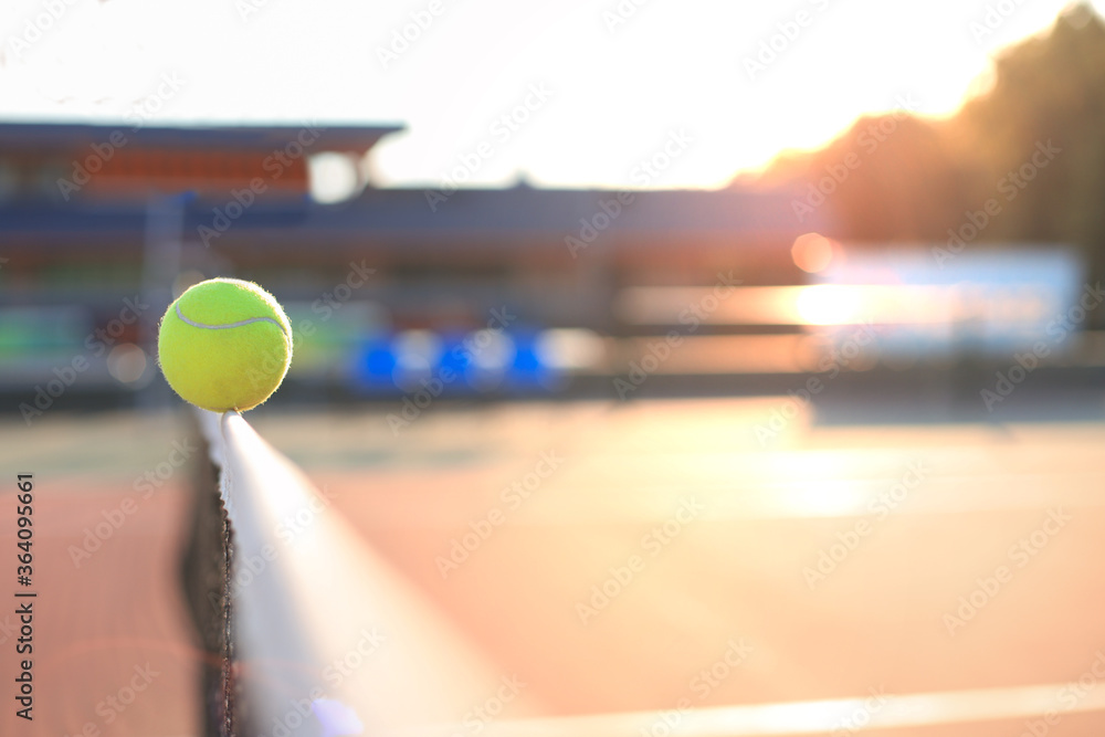 Bright greenish yellow tennis ball hitting the net.