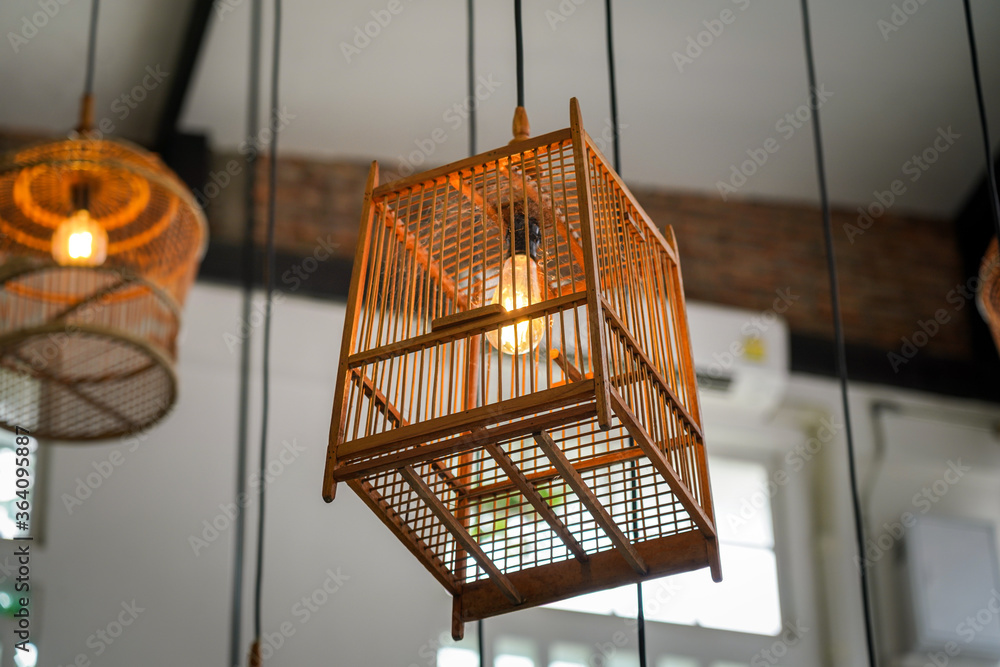 Lighting bulb in warm light color inside the wooden bird's cage design, using for home or cafe decoration. Selective focus on the bulb's part, Interior object photo.