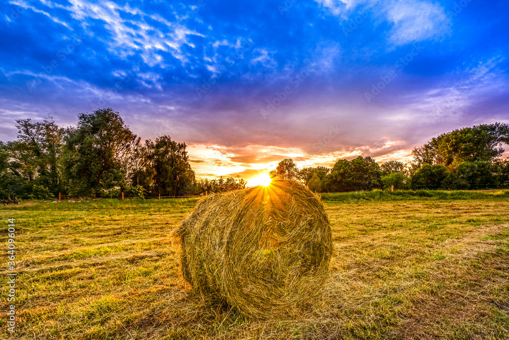 Strohballen auf einem Feld mit Sonnenuntergang