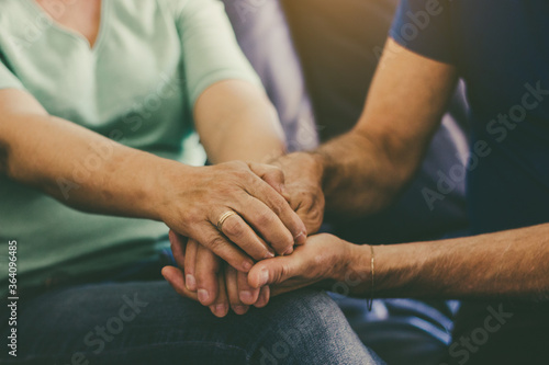 Close up caucasian woman and man in love sitting on couch two people holding hands. 