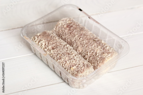 Uncooked meat roulade in plastic tray. Rolled meat with a filling of cheese and ham.