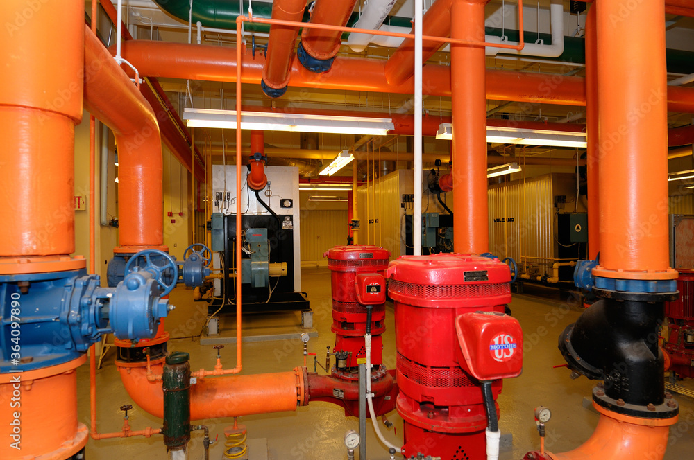 Row of furnaces and hot water pipes in the boiler room of a highrise office building Row of furnaces and hot water pipes in the boiler room of a highrise office building