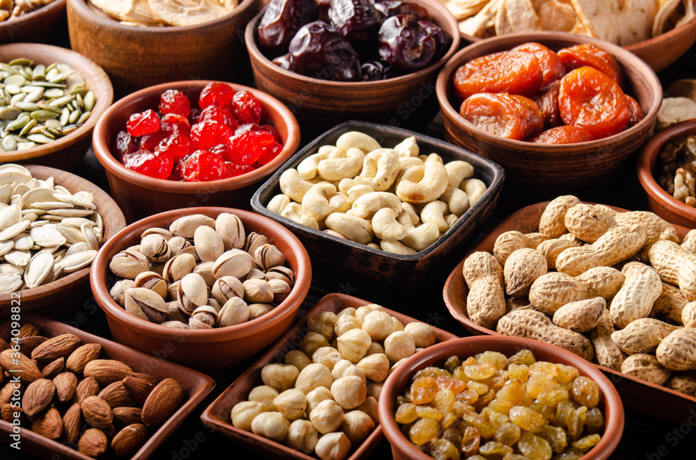Different nuts seeds and dried fruits in bowls on wooden kitchen table Different nuts seeds and dried fruits in bowls on wooden kitchen table