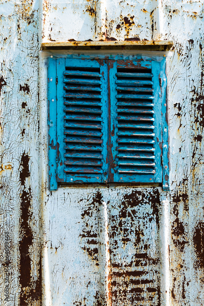 Naklejka premium Old wooden window painted blue with rusty lock. Texture, wall of an old wooden house with shuttered windows, painted blue.