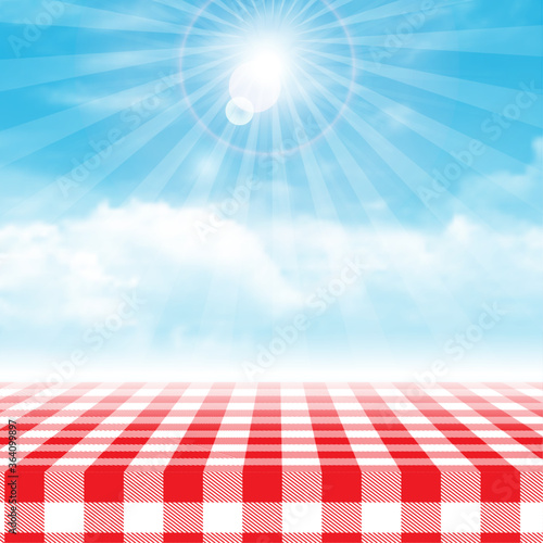 Gingham picnic table against blue cloudy sky