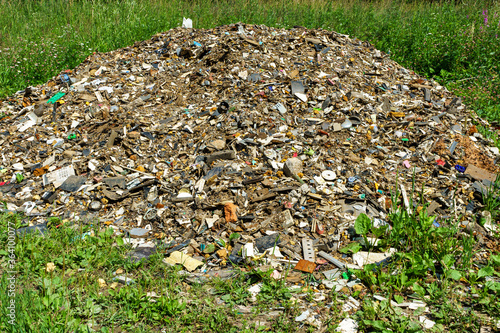 A large gray pile of garbage in the middle of a wonderful field, an illustration of environmental pollution in Russia