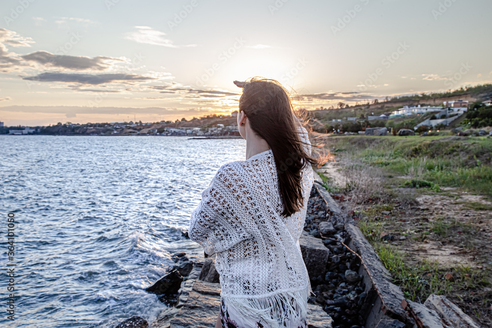 Beautiful young woman by the sea at sunset.