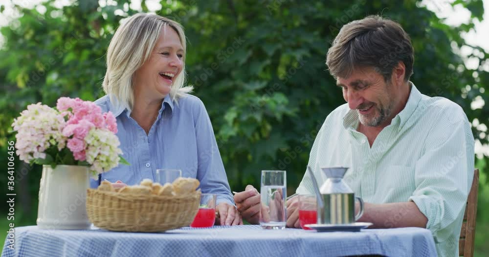 Authentic shot of lovely happy mature couple is enjoying time together and having a romantic dinner to celebrate their anniversary and timeless love on a green nature background. Authentic shot of lovely happy mature couple is enjoying time together and having a romantic dinner to celebrate their anniversary and timeless love on a green nature background.