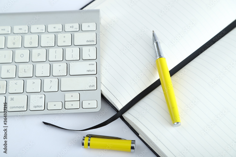 White office desk table with blank notebook, computer keyboard and other office supplies. Top view with copy space, flat lay. White office desk table with blank notebook, computer keyboard and other office supplies. Top view with copy space, flat lay.