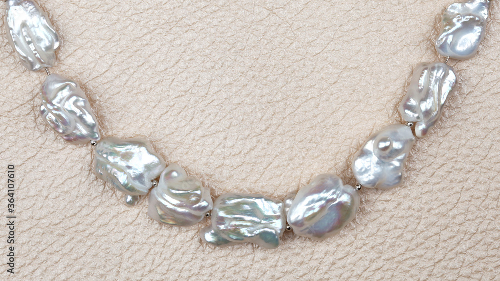 Curve of baroque pearls on beige leather background Curve of baroque pearls on beige leather background