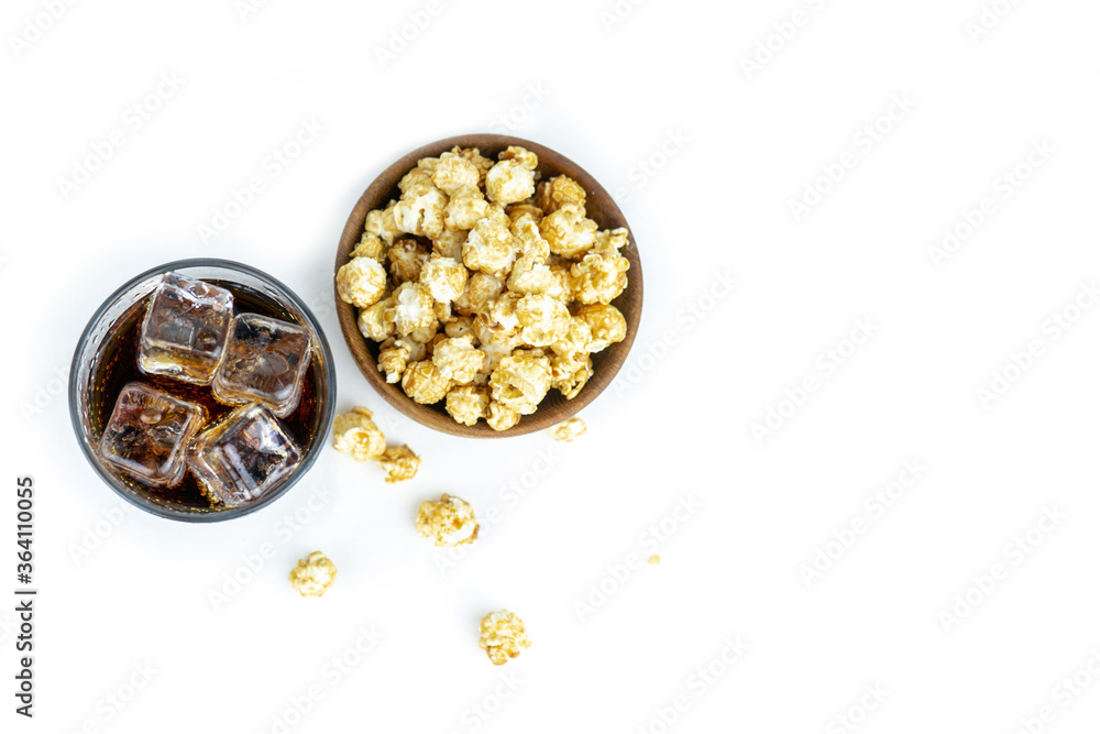 glass of cold refreshing cola soda with ice, wooden bowl of fresh popcorn with caramel, top flat shot, top view glass of cold refreshing cola soda with ice, wooden bowl of fresh popcorn with caramel, top flat shot, top view