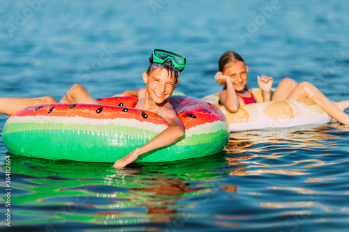Swimming, summer vacation happy kids boy and girl playing and swimming on the sea with inflatable circles. The concept of summer vacation © Shopping King Louie