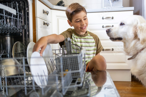 Cuadro en lienzo Little boy loading the dishwasher at home