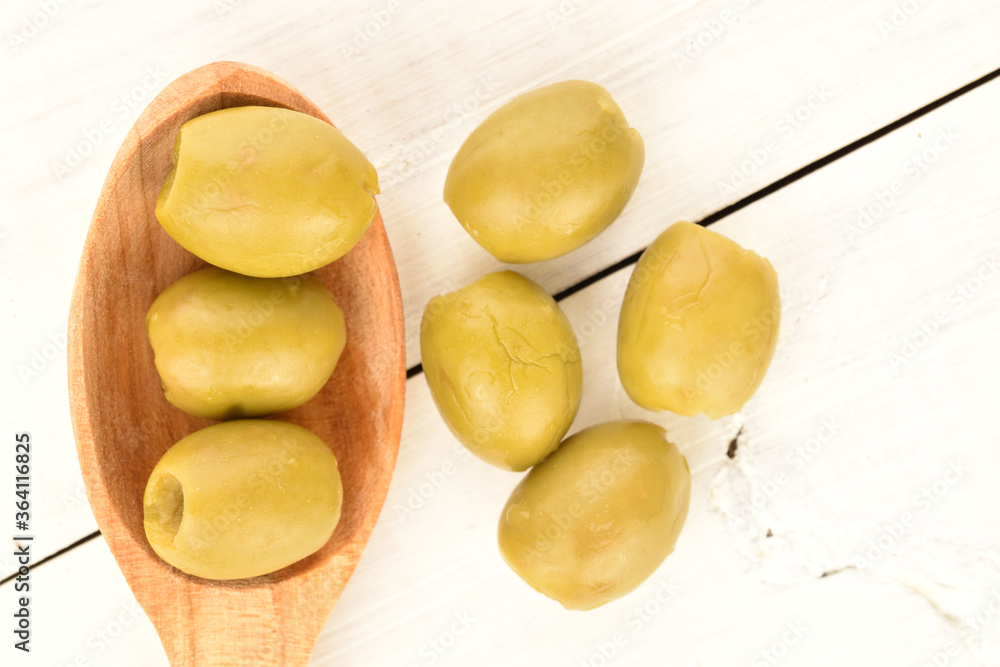 Tinned green pitted olives, close-up, on a wooden table. Tinned green pitted olives, close-up, on a wooden table.