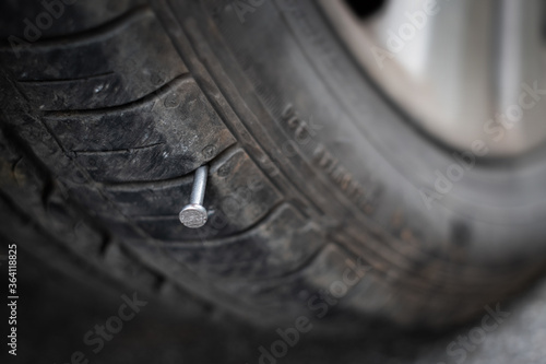 Close up button head needle metal nail stuck to puncture into wheel tire