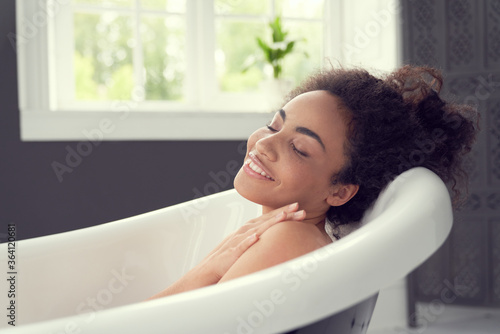 Happy young lady enjoying time alone in bathroom