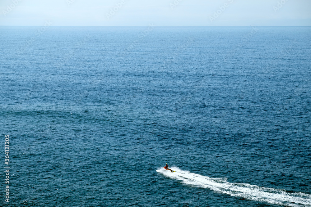 Jet ski with two life guards. Hazy distant horizon. Helicopter view.