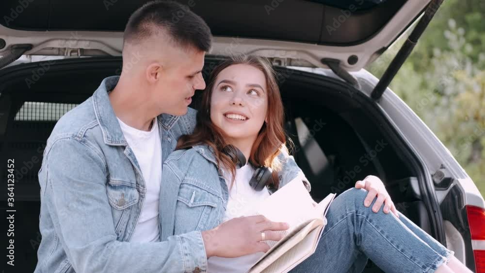 People wear denim clothing. Couple is in forest. Boy and girl sit in trunk and read book. People wear denim clothing. Couple is in forest. Boy and girl sit in trunk and read book.