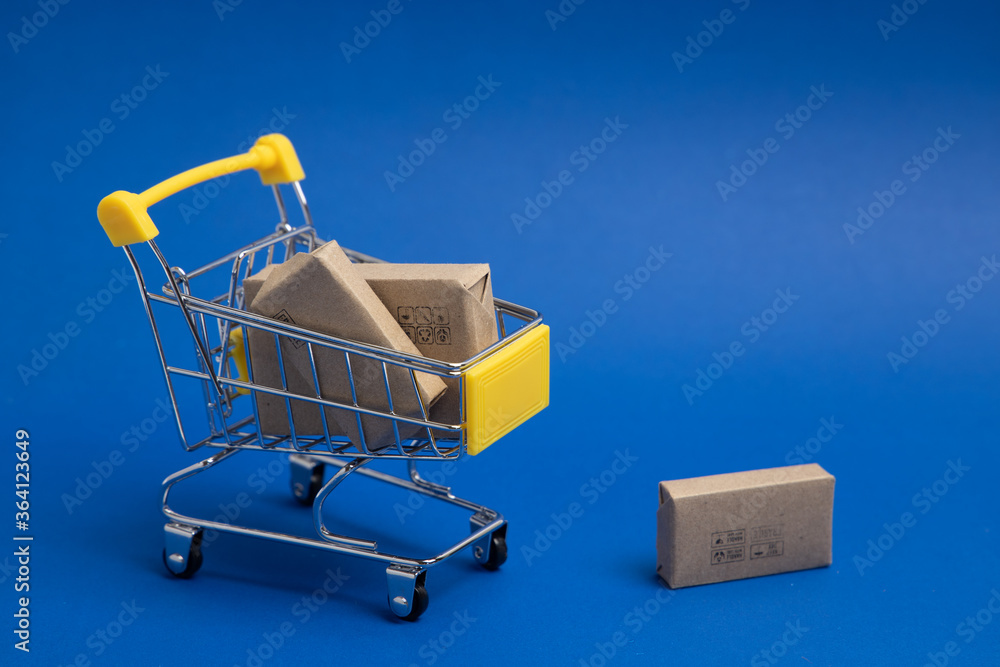 Yellow shopping cart or trolley and small , Product box, Package box , Isolated on blue background .Shopping symbols in shopping malls and general business concept.