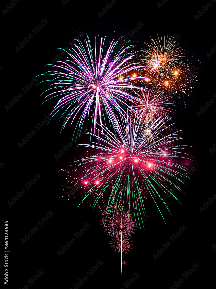 Colorful purple and green fireworks display light up the sky during night time celebration