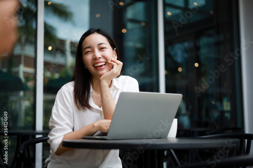 Asian woman working with computer laptop and drinking coffee in coffee shop cafe smile and happy face