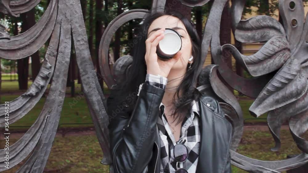 young beautiful woman drinking coffee near an ornate lattice on the street portrait