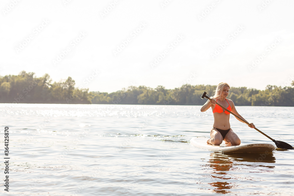 Naklejka premium A beautiful woman practicing paddle on a beautiful sunny day