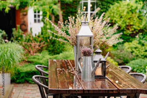 bouquet of dried flowers and candles on table in yard in rain in summer.