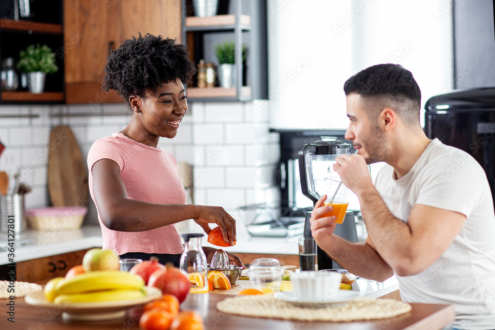 Multiethnic couple in the kitchen prepare smoothie with healthy tropical fruits Multiethnic couple in the kitchen prepare smoothie with healthy tropical fruits