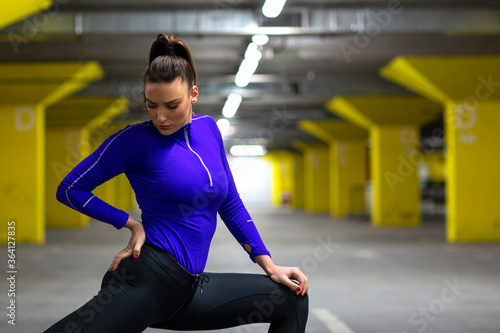 Fit girl in sportswear exercise in public garage to stay fit