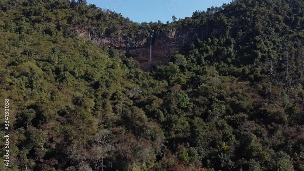 waterfall in winter with thin stream over cliff forest clear skies added out of focus with grain waterfall in winter with thin stream over cliff forest clear skies added out of focus with grain