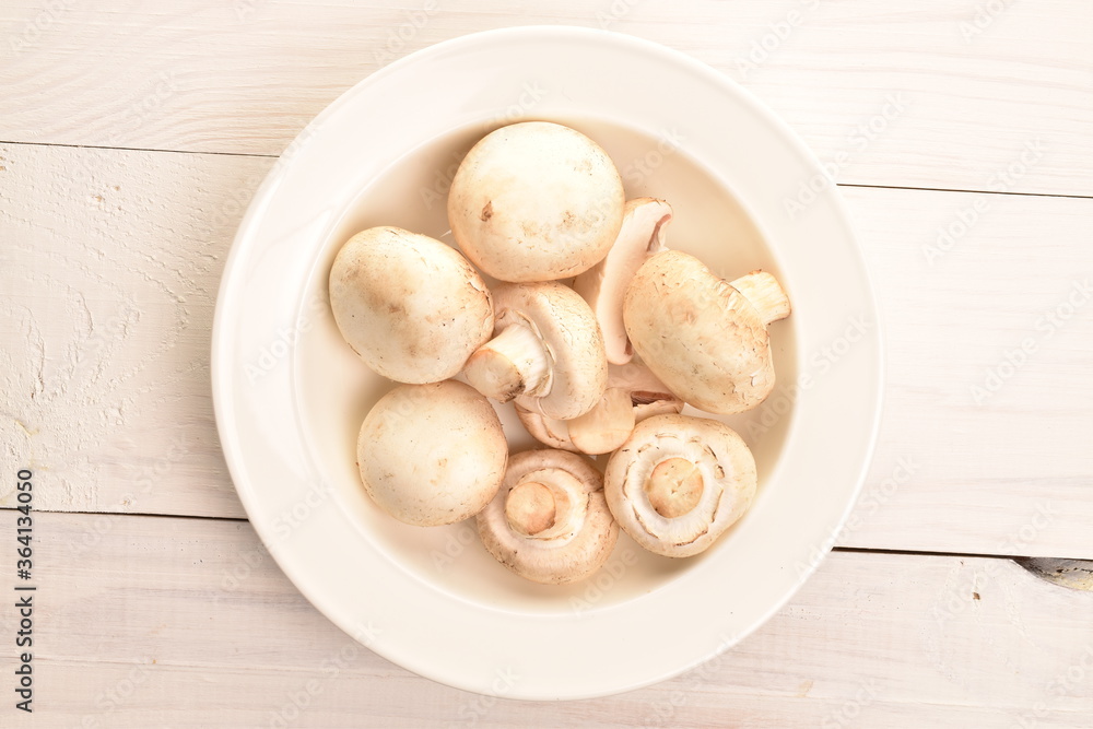 Freshly cut mushrooms on a plate, close-up, on a white wooden table. Freshly cut mushrooms on a plate, close-up, on a white wooden table.