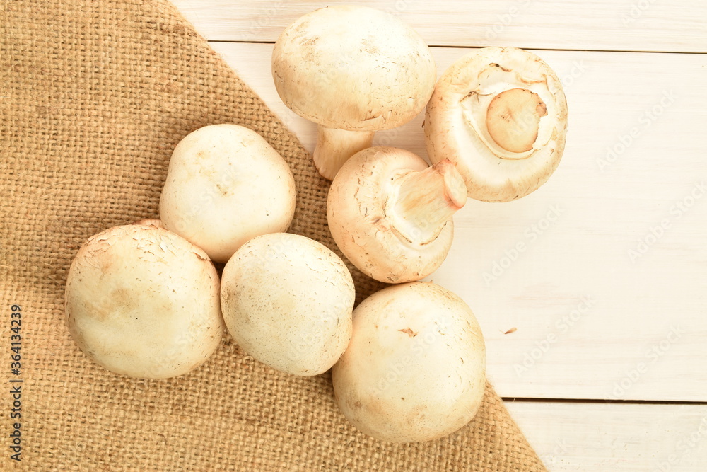 Freshly cut mushrooms, close-up, on jute fabric on a white wooden table. Freshly cut mushrooms, close-up, on jute fabric on a white wooden table.