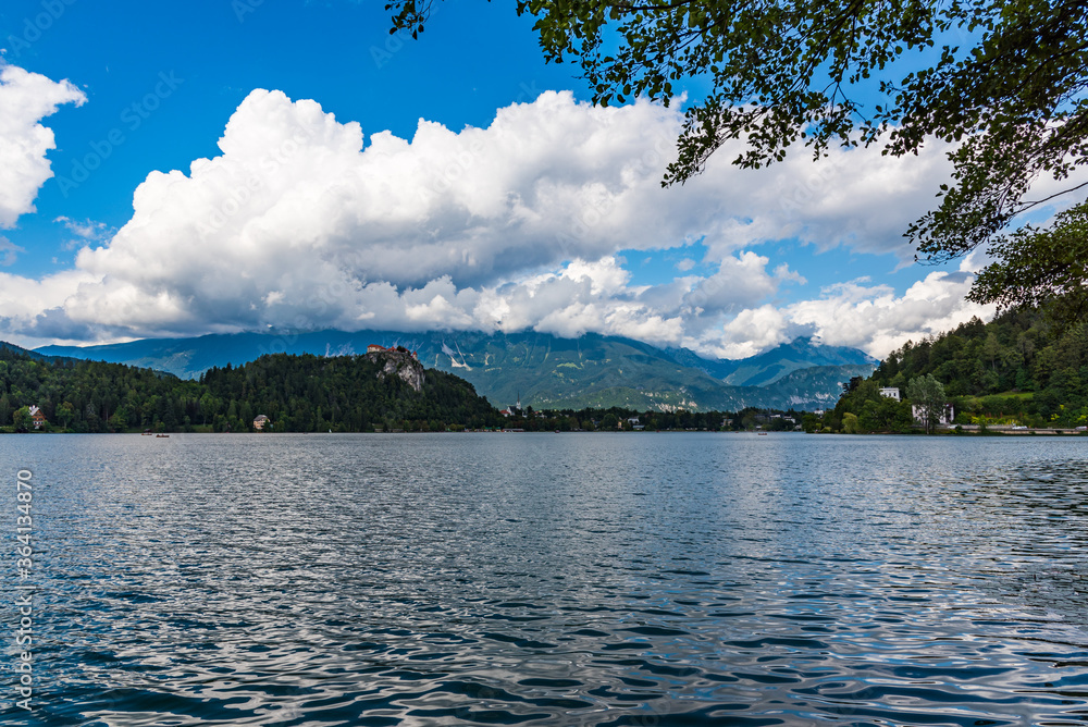 Big lake with green mountains on the background under white clouds